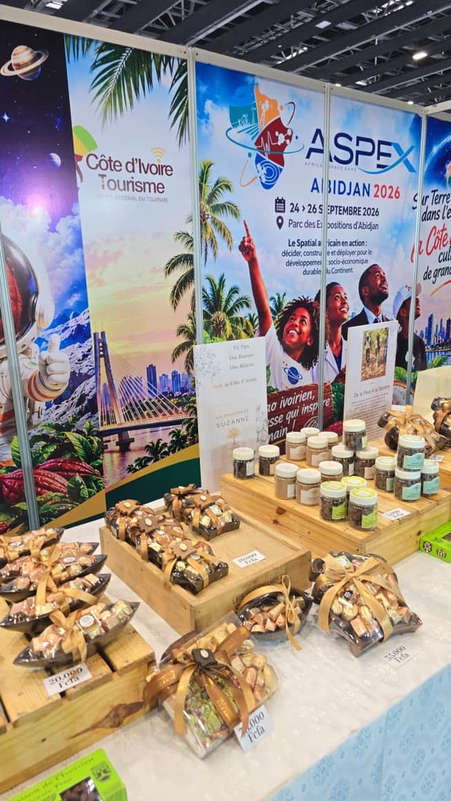 Stand de Côte d’Ivoire Tourisme présentant des douceurs emballées devant l’affiche ASPAEX Abidjan 2026