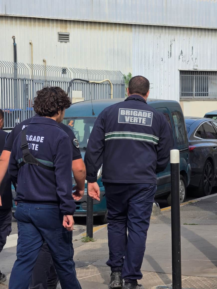Trois agents de la Brigade verte marchant devant une clôture industrielle