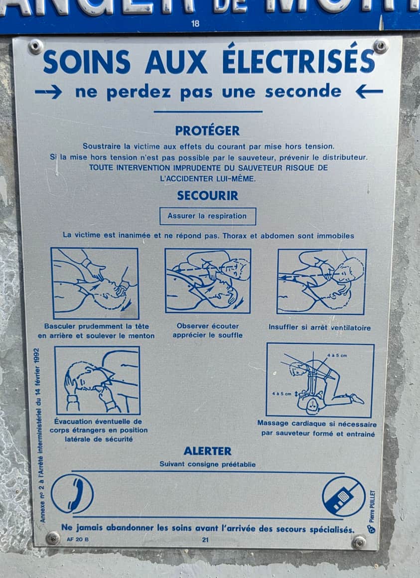 Plaque métallique bleue et argent intitulée Soins aux électrisés, avec textes et dessins de gestes de secours