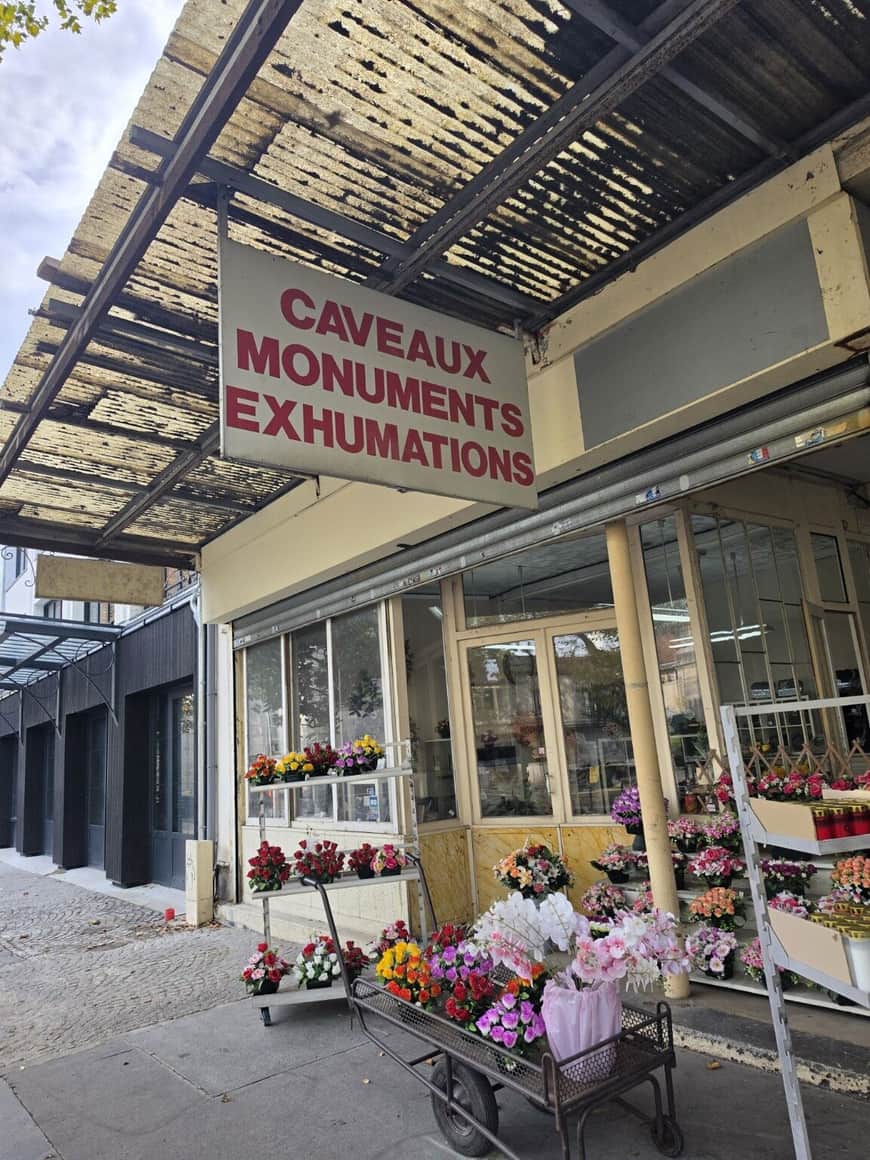 Devanture funéraire présentant fleurs artificielles et enseigne Caveaux Monuments Exhumations