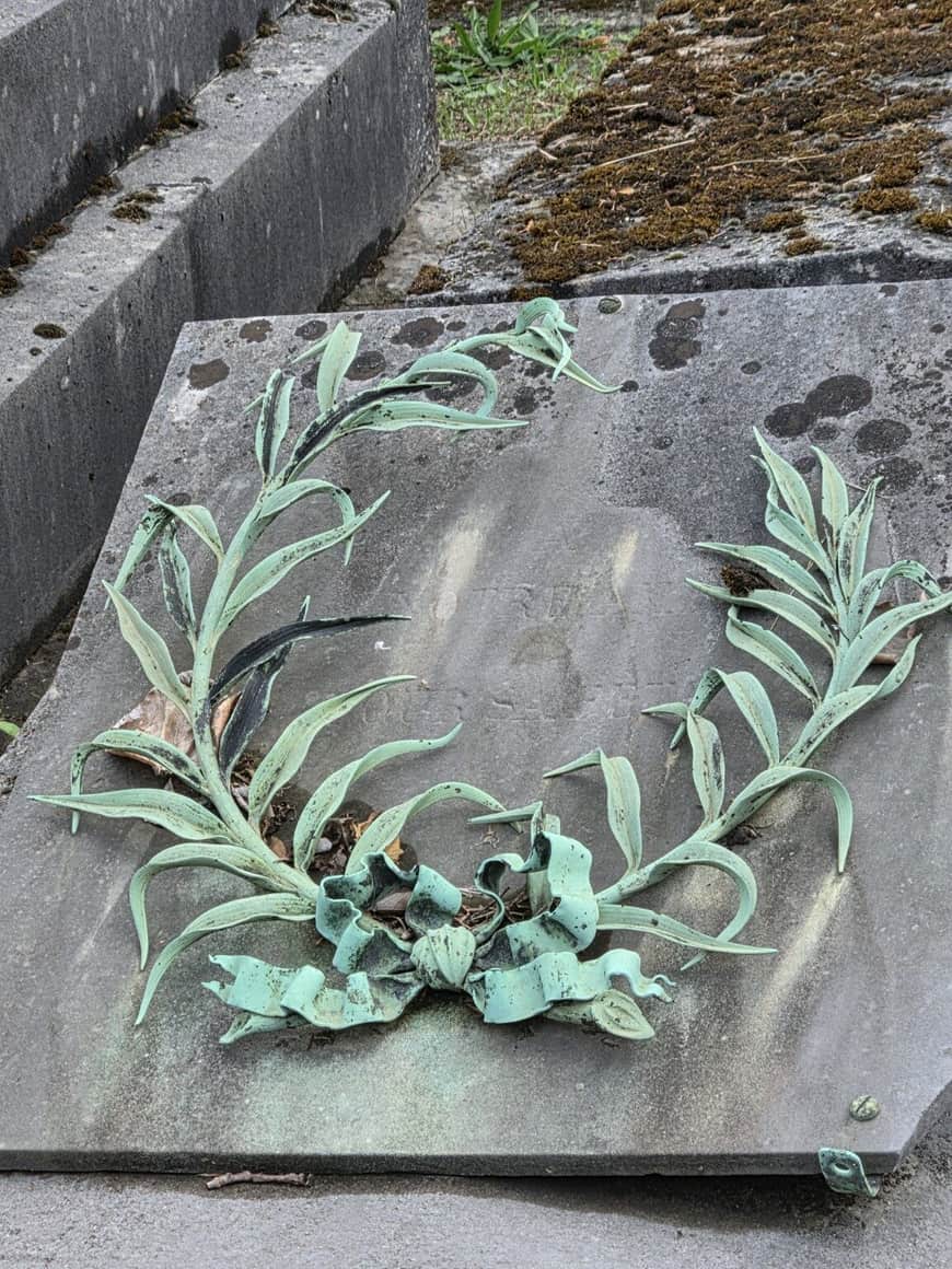 Dalle funéraire ornée d’un bouquet et de longues feuilles en métal verdi