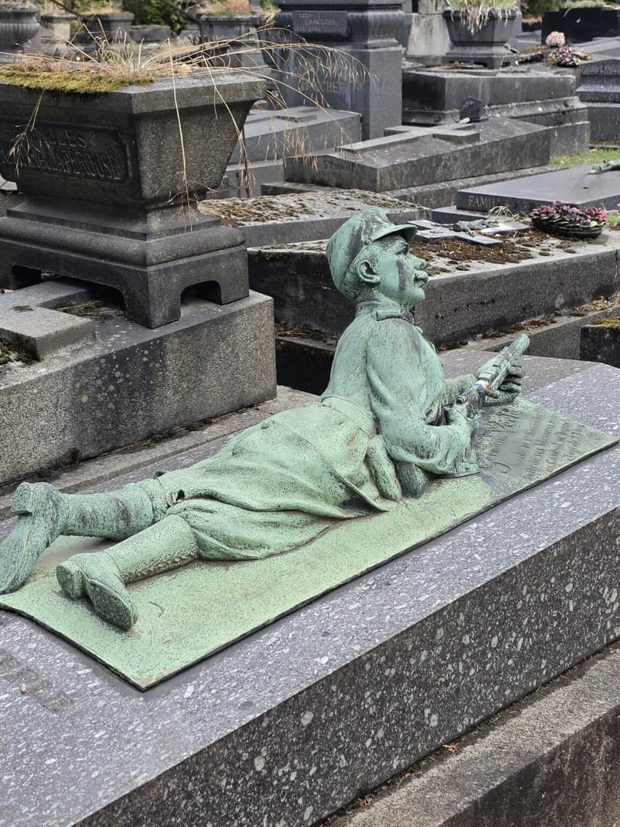 Vue latérale d’une statue de soldat couché sur une tombe au milieu d’autres monuments