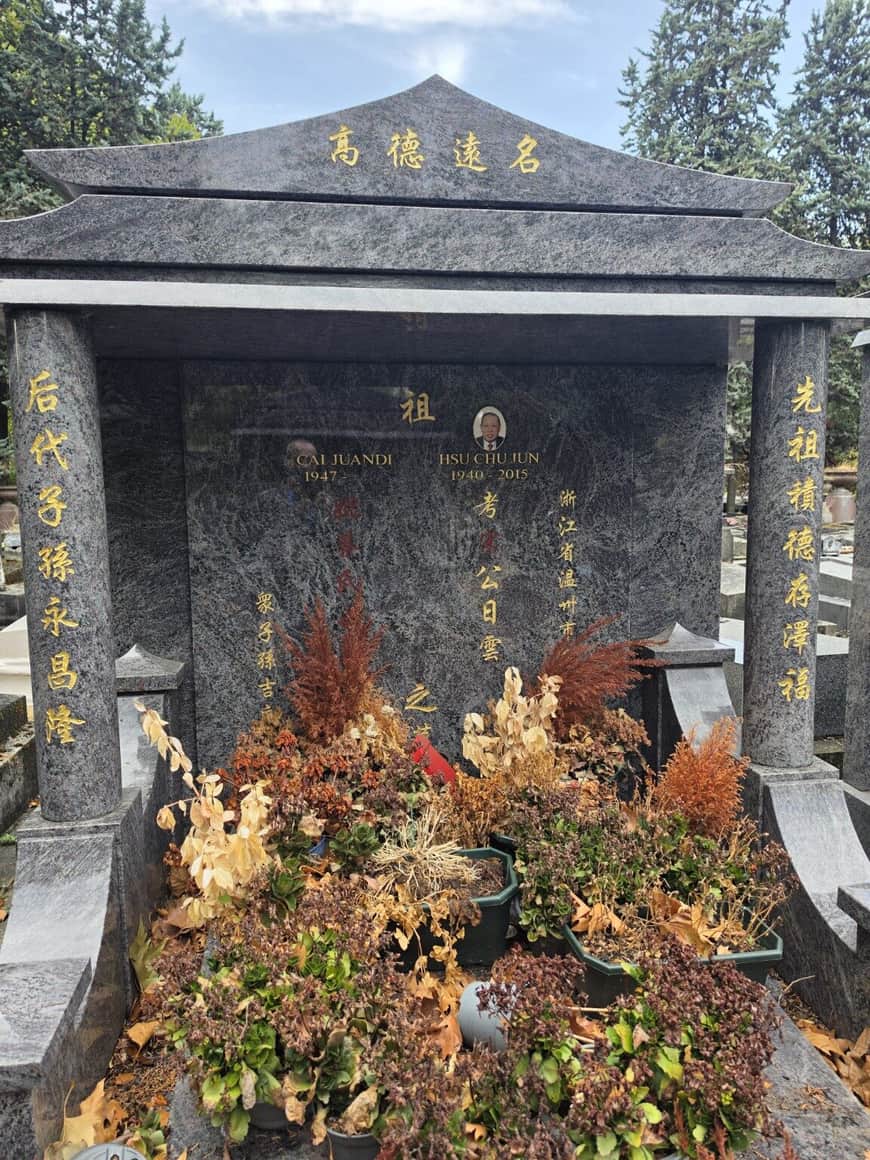 Tombe chinoise en pierre sombre avec inscriptions dorées, portraits et fleurs fanées