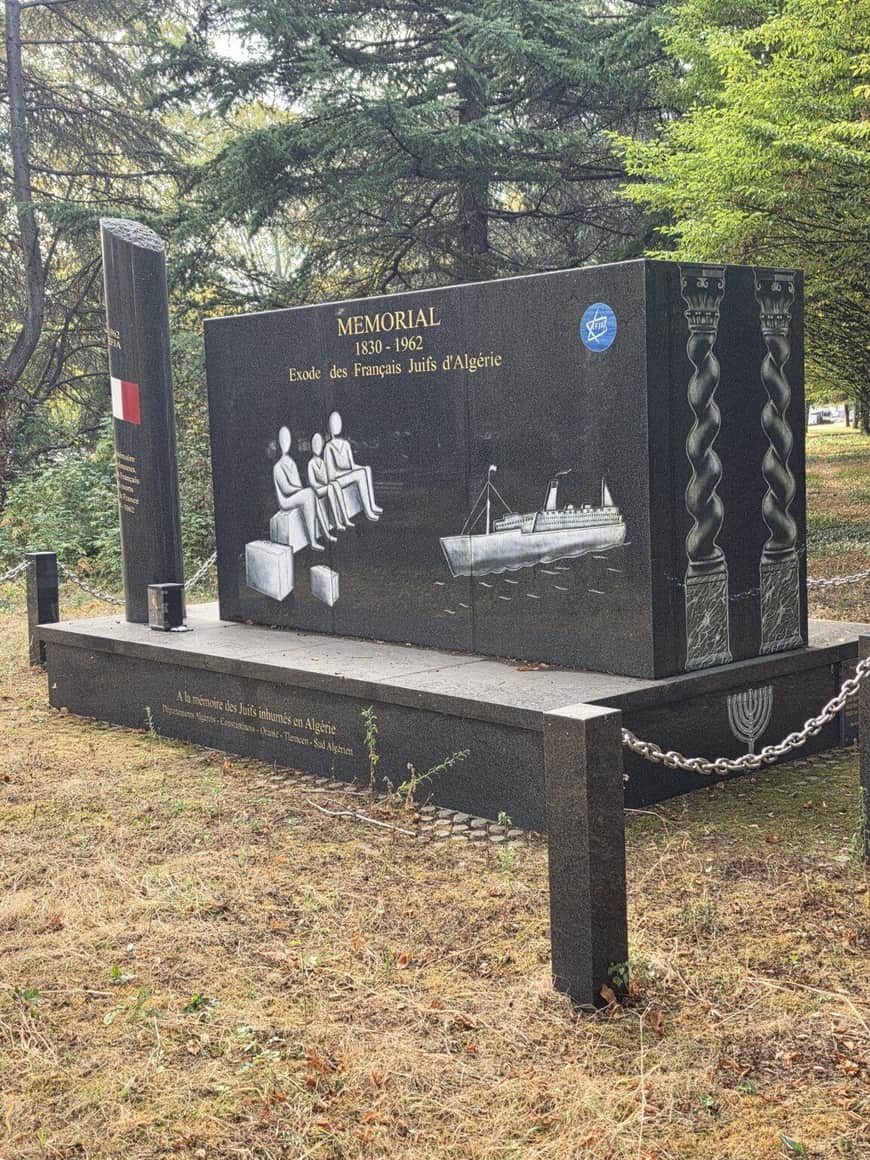 Mémorial noir de 1830–1962 consacré à l’exode des Français juifs d’Algérie, avec silhouettes, valises, bateau, étoiles de David et menorah