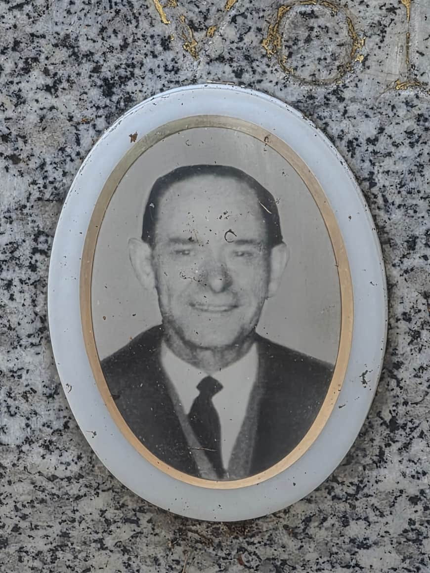 Portrait funéraire ovale en noir et blanc d’un homme en costume et cravate, fixé sur une pierre mouchetée