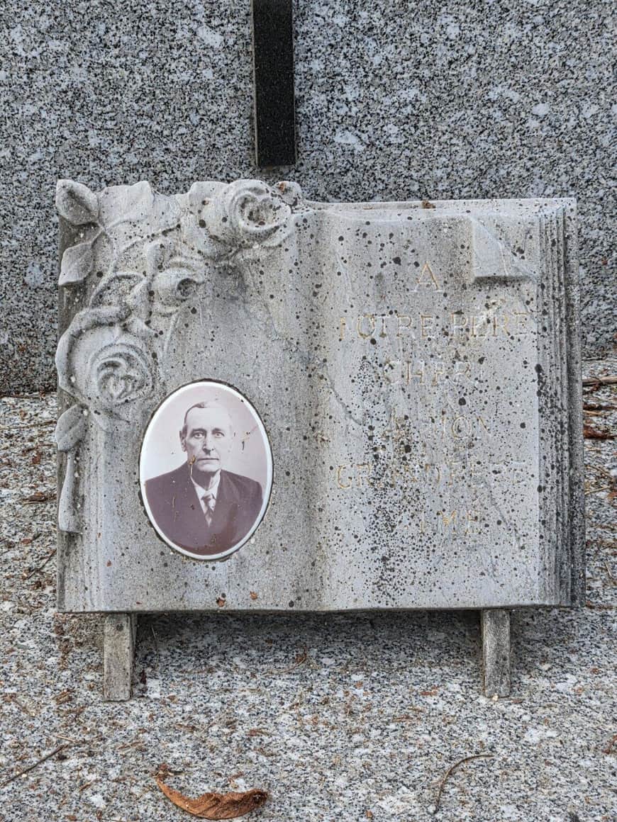 Plaque funéraire sculptée comme un livre ouvert, ornée de roses et d’un portrait ovale d’homme