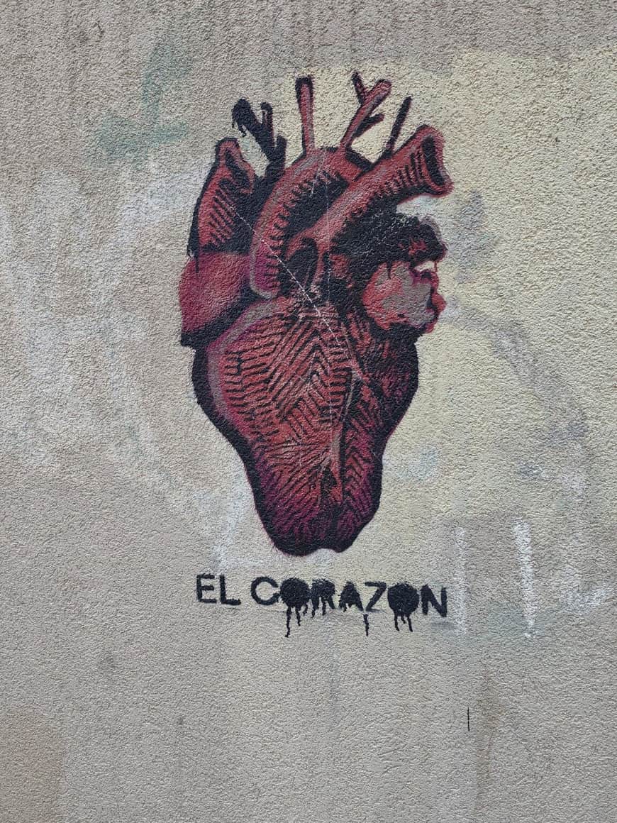 Pochoir rouge et noir d’un cœur anatomique accompagné des mots El Corazón sur un mur beige