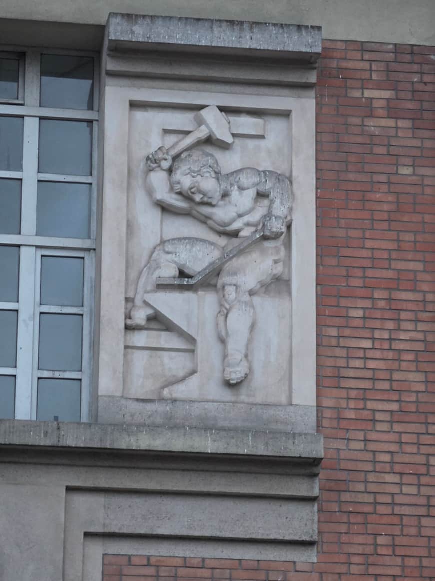 Relief de pierre représentant une figure maniant un marteau au-dessus d’un établi