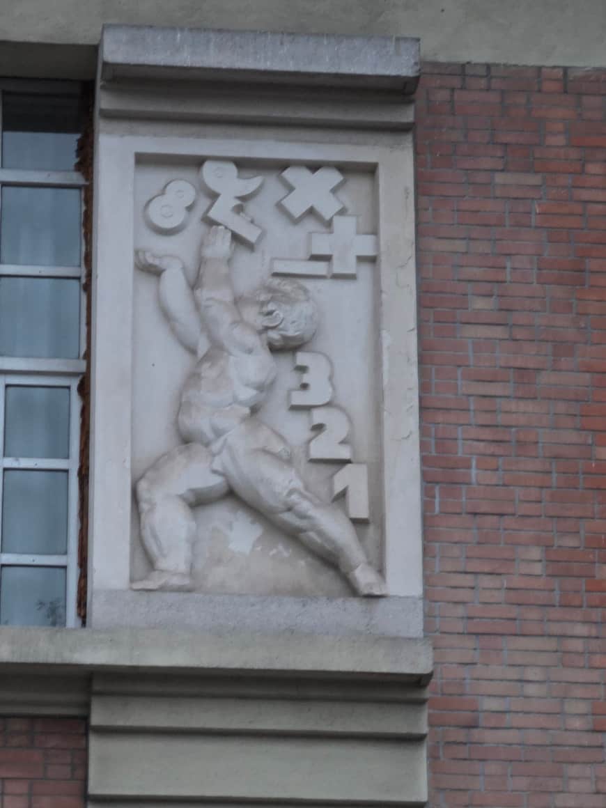 Relief de pierre représentant une figure entourée de chiffres et de signes arithmétiques