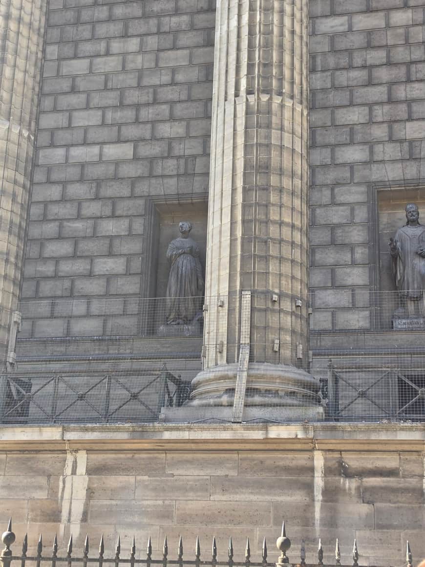 Deux statues dans des niches entre des colonnes, derrière des grilles de protection
