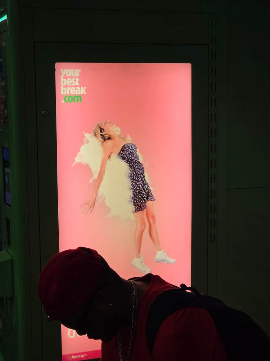 Silhouette penchée devant une publicité lumineuse rose représentant un corps rejeté en arrière