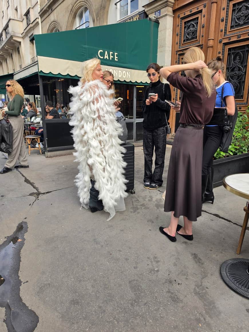 Groupe réuni devant le café autour d’une personne vêtue d’un ample costume de plumes blanches