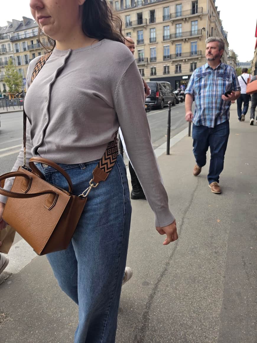 Passante au premier plan masquant partiellement deux hommes sur un trottoir parisien