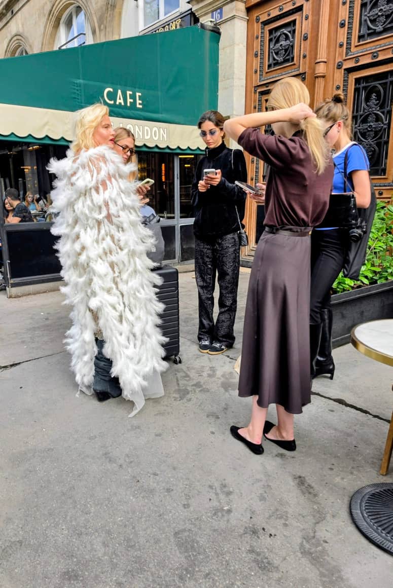 Groupe devant le Café Paris London autour d’une personne vêtue de plumes blanches