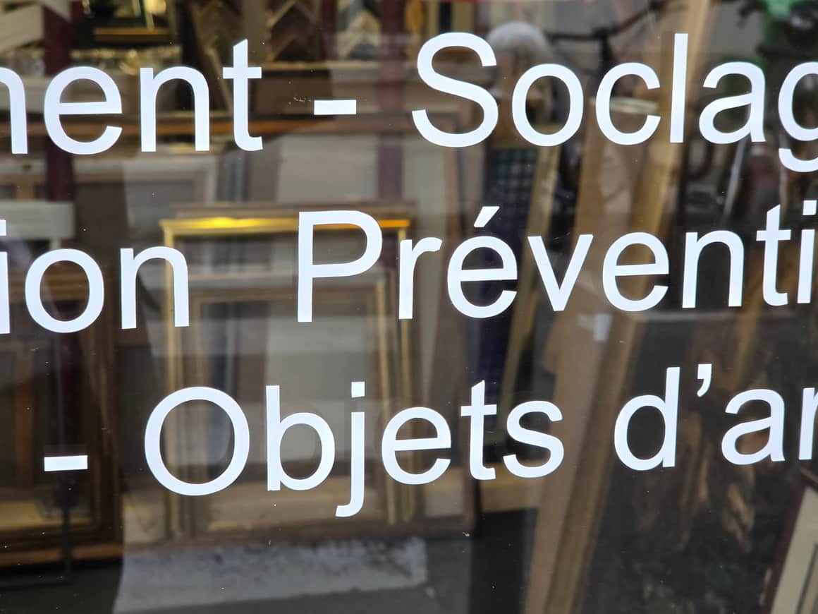 Inscription blanche sur une vitrine mentionnant soclage, conservation préventive et objets d’art