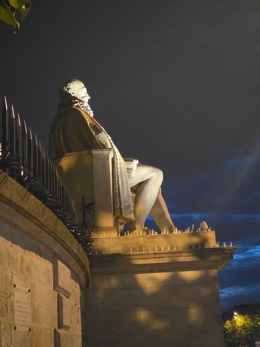 Statue monumentale assise éclairée de nuit sous un ciel nuageux