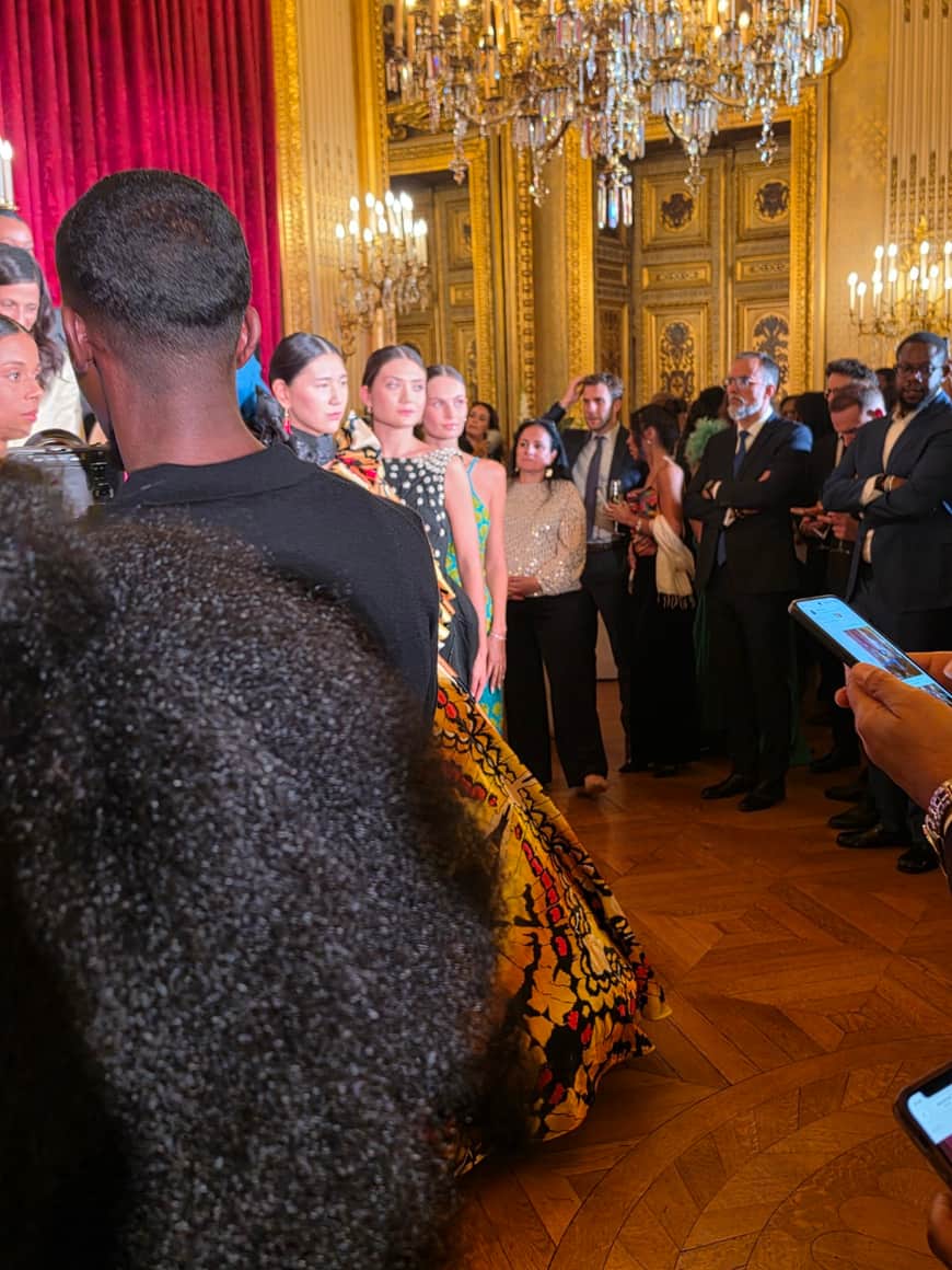 Robe imprimée vue depuis le public dans un salon à velours rouge et dorures