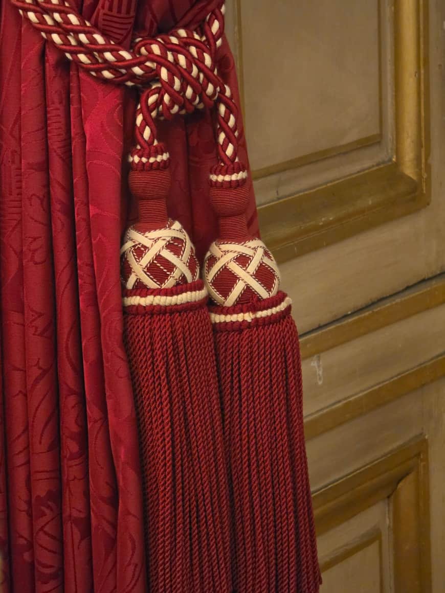 Deux embrasses rouges et crème à glands maintenant un rideau de velours rouge
