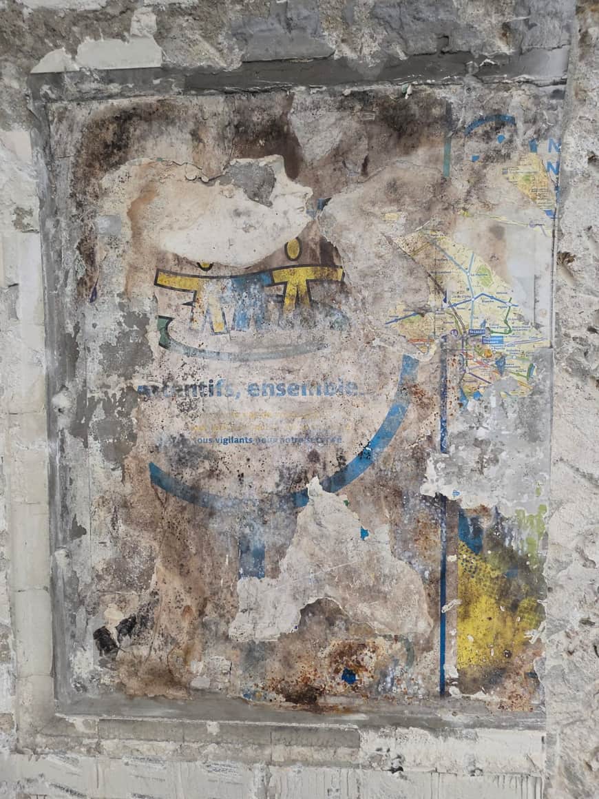 Affiche presque entièrement effacée sur un mur de pierre.