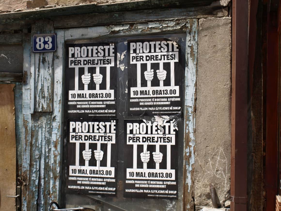 Quatre affiches albanaises de protestation sur une porte usée.