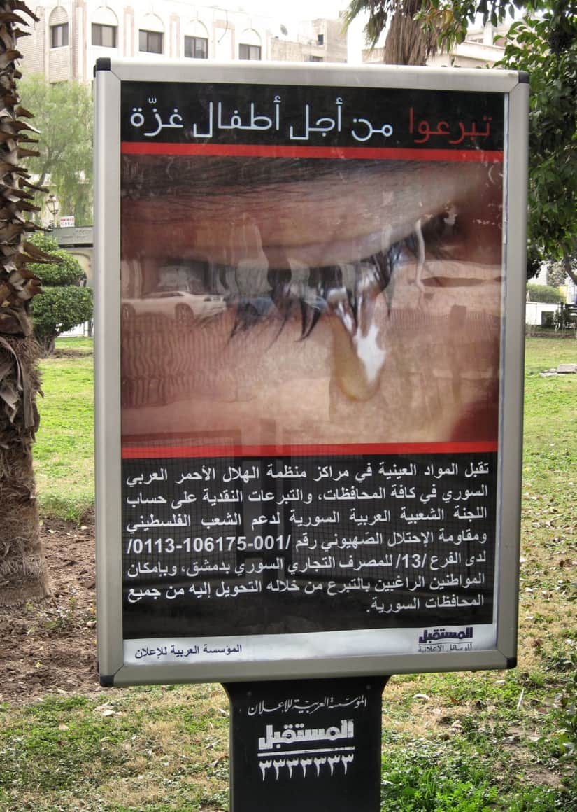 Affiche en caractères arabes derrière une vitre.
