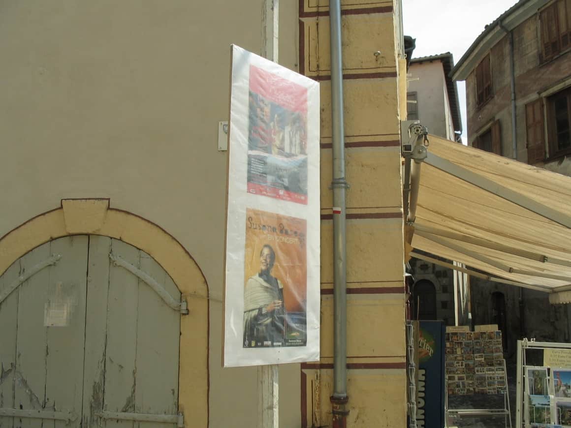 Affiche d’exposition dans une rue étroite.
