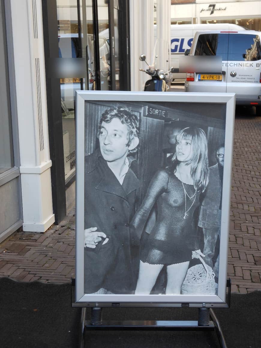 Photographie en noir et blanc exposée dans la rue, plaques masquées.