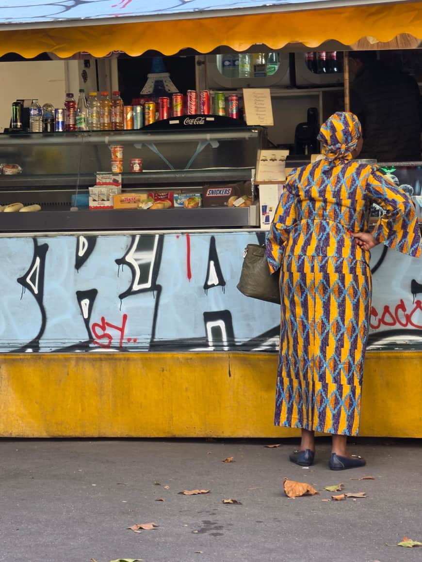 Femme vêtue d’un ensemble coloré devant le comptoir jaune d’une buvette