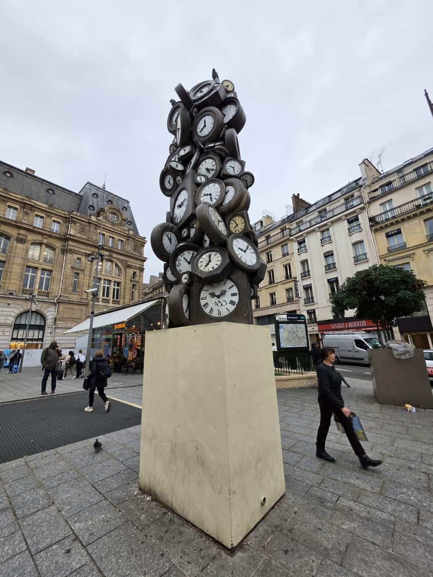 Sculpture publique composée d’une accumulation d’horloges sur un socle