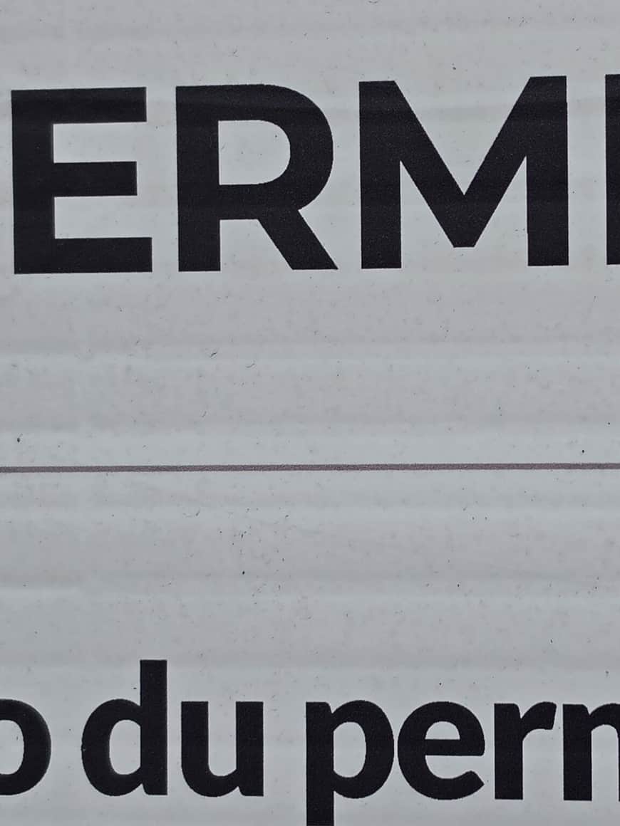 Fragments de grandes lettres noires imprimées sur un support blanc, coupées par le cadrage