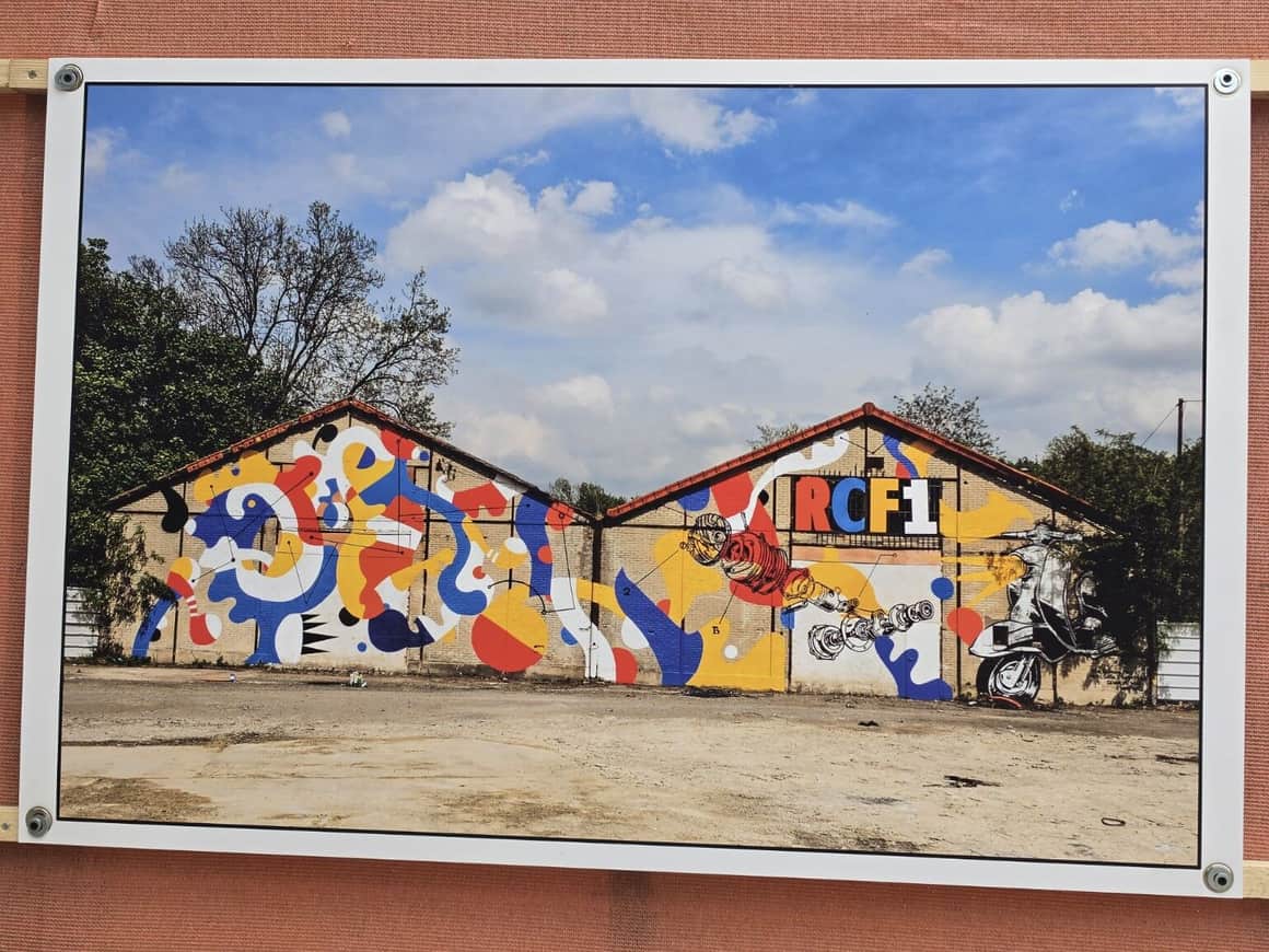 Photographie exposée d’un double hangar couvert d’une peinture murale abstraite rouge, jaune, bleue, blanche et noire