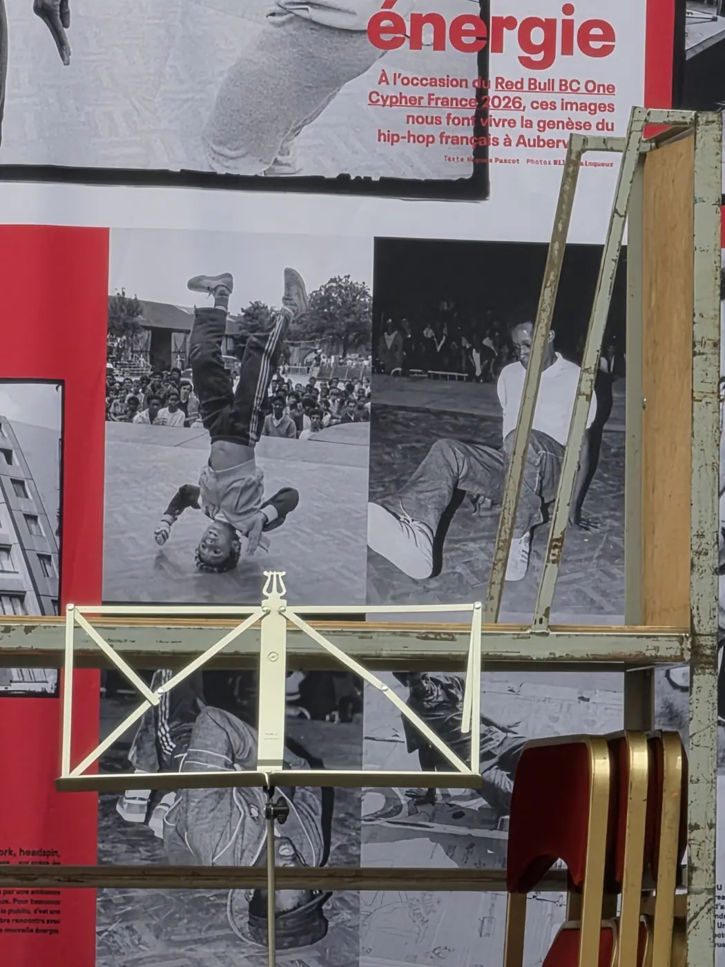 Photographies en noir et blanc et texte d’exposition sur un panneau, coupés par une barrière claire