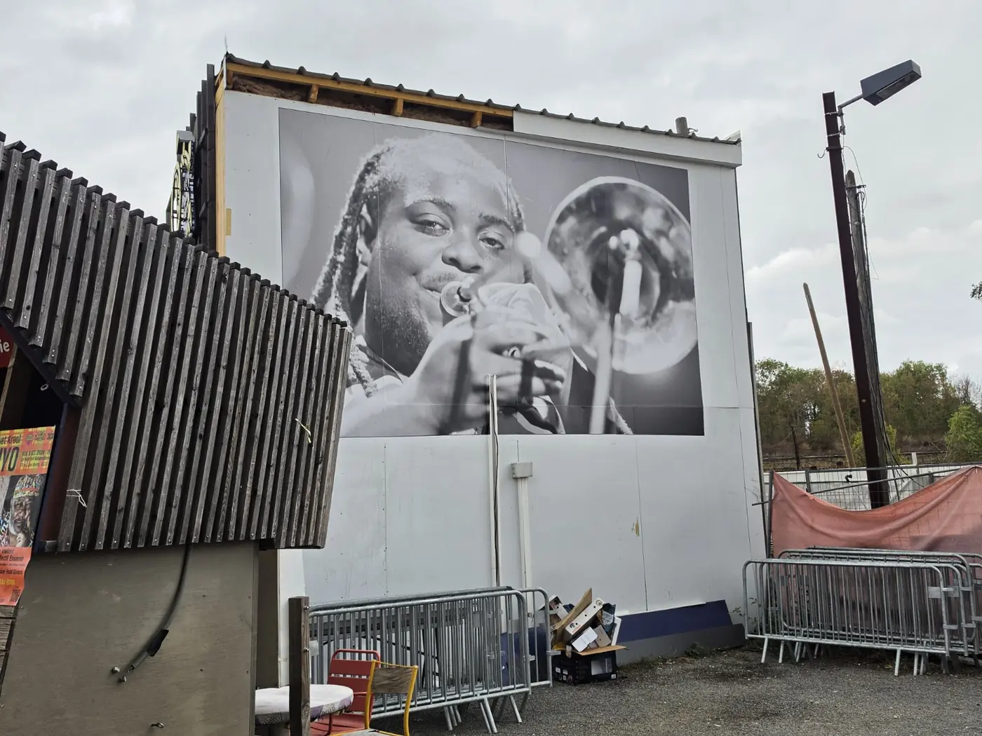 Portrait photographique monumental d’un musicien avec une trompette, installé sur un panneau au bord de la rue