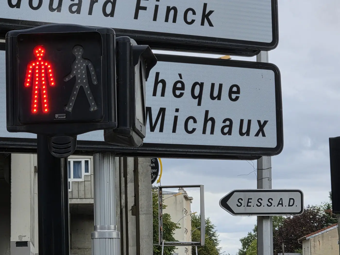 Feu piéton rouge devant plusieurs panneaux de rue et d’établissement