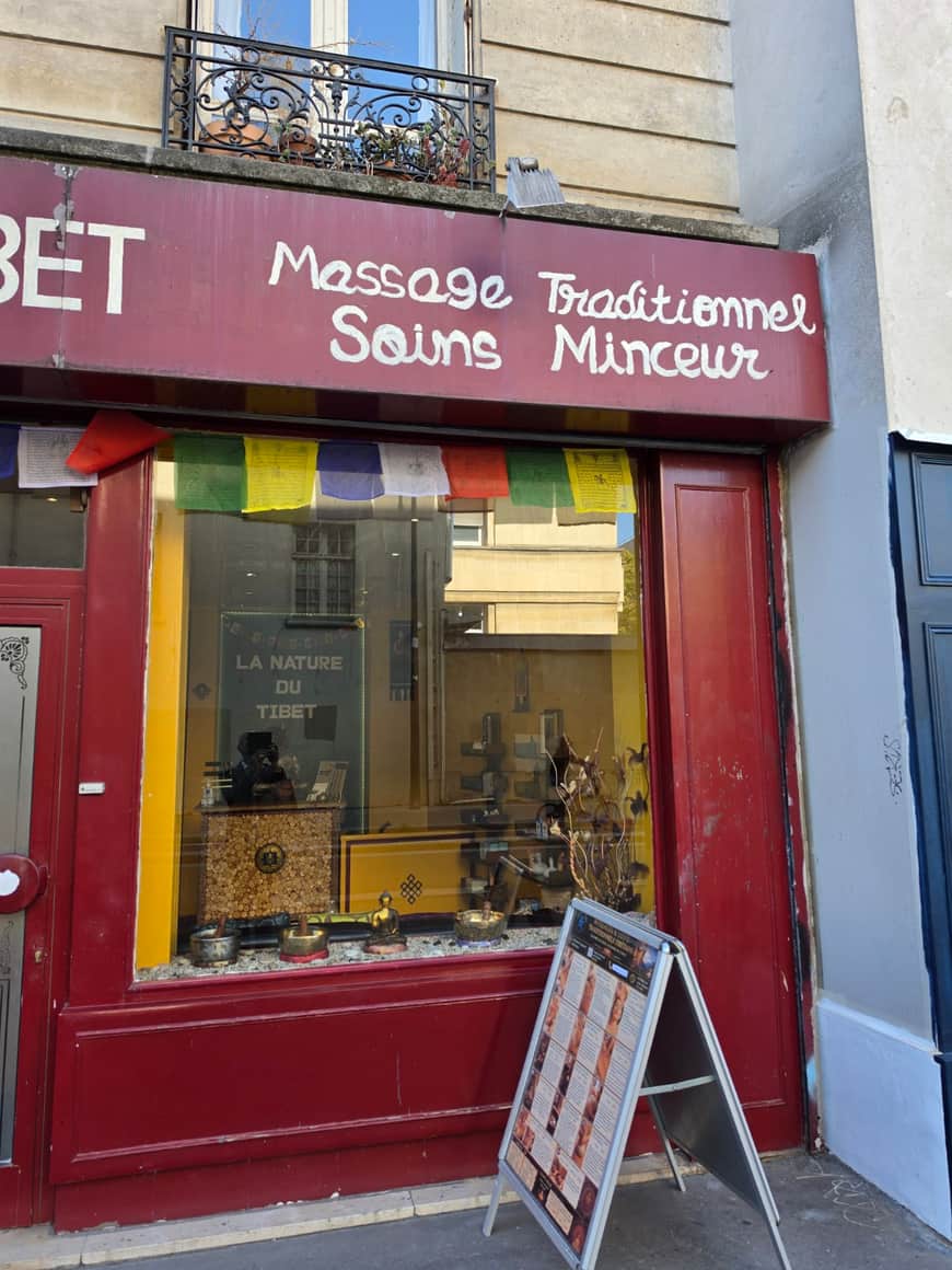 Seconde partie de la façade rouge de La Nature du Tibet avec vitrine, objets, affiche et panneau de soins