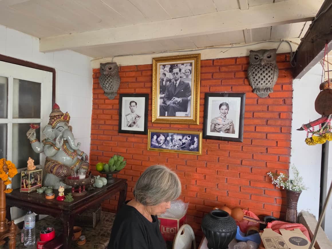 Intérieur chargé : mur de brique, portraits encadrés et objets.