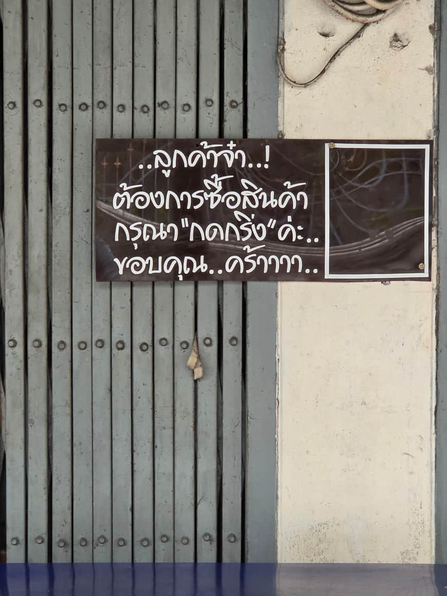Grille métallique avec une inscription en thaï sur une ardoise.