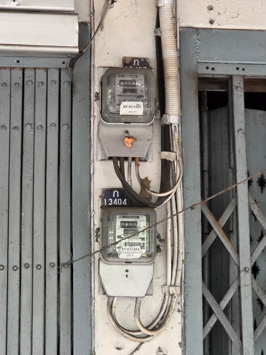 Compteurs électriques et câbles fixés sur un mur extérieur.