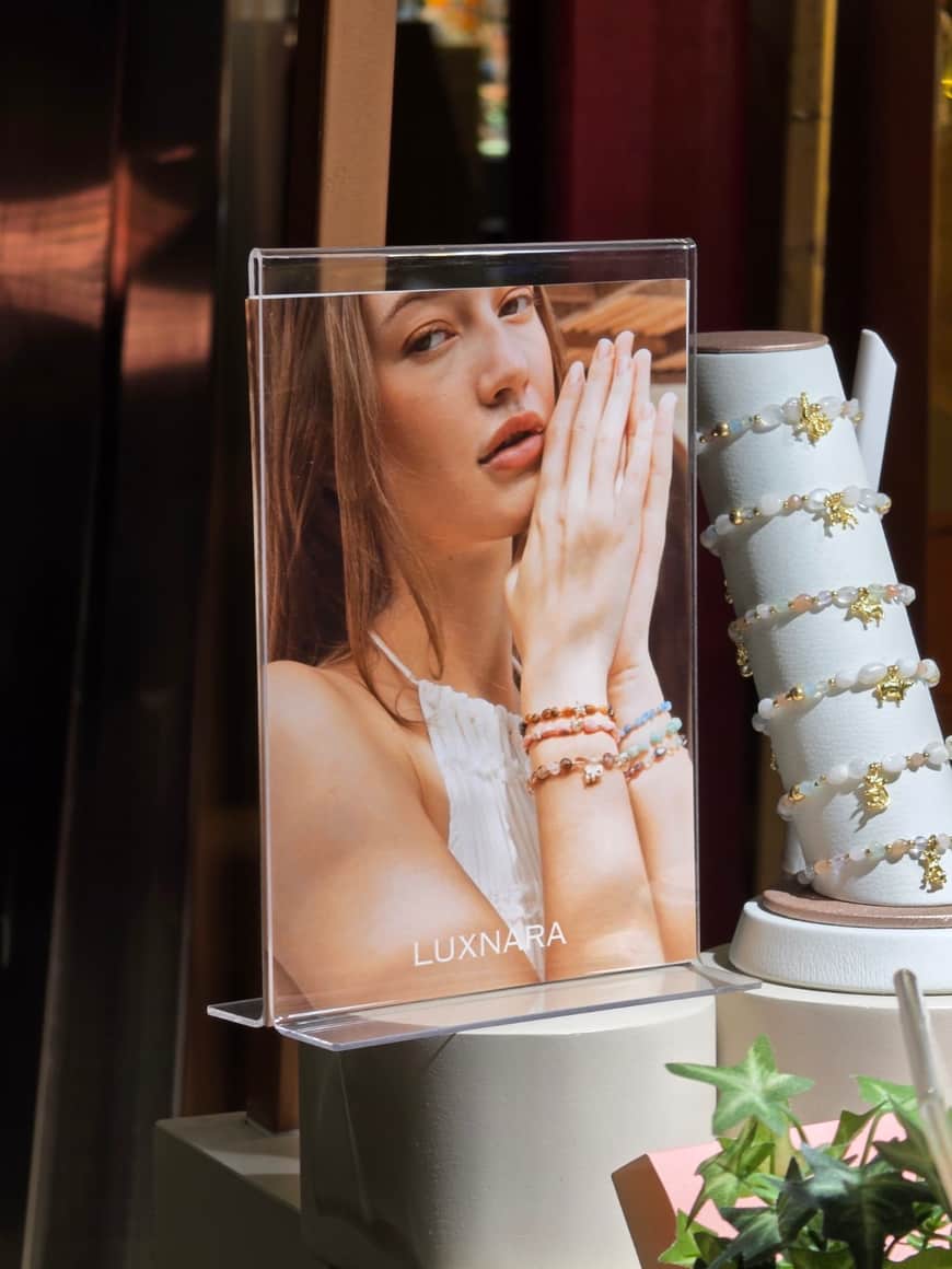 Affiche de mode et présentoir de bijoux en vitrine.