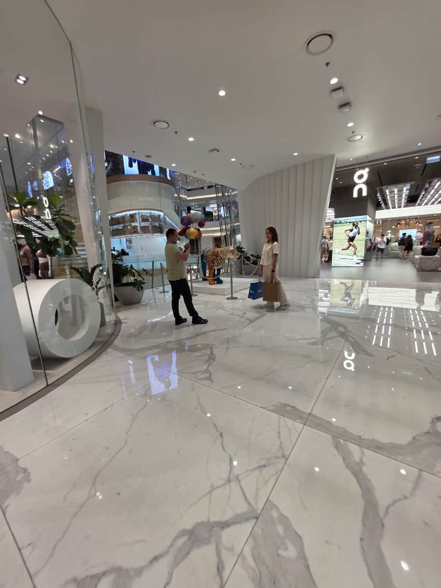 Visiteurs et vitrines dans une galerie au sol réfléchissant.