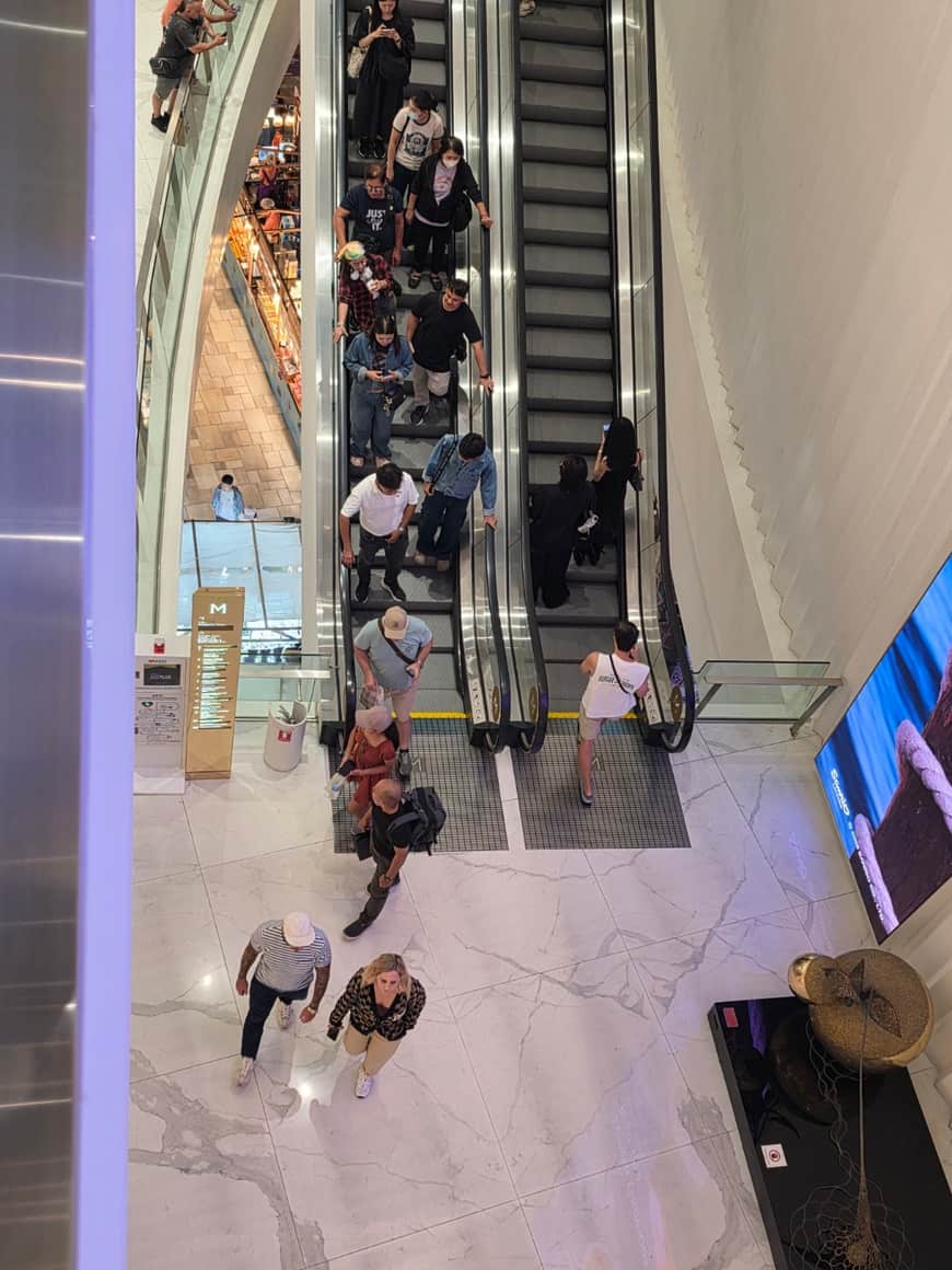 Vue plongeante sur des escalators et les niveaux d’une galerie.