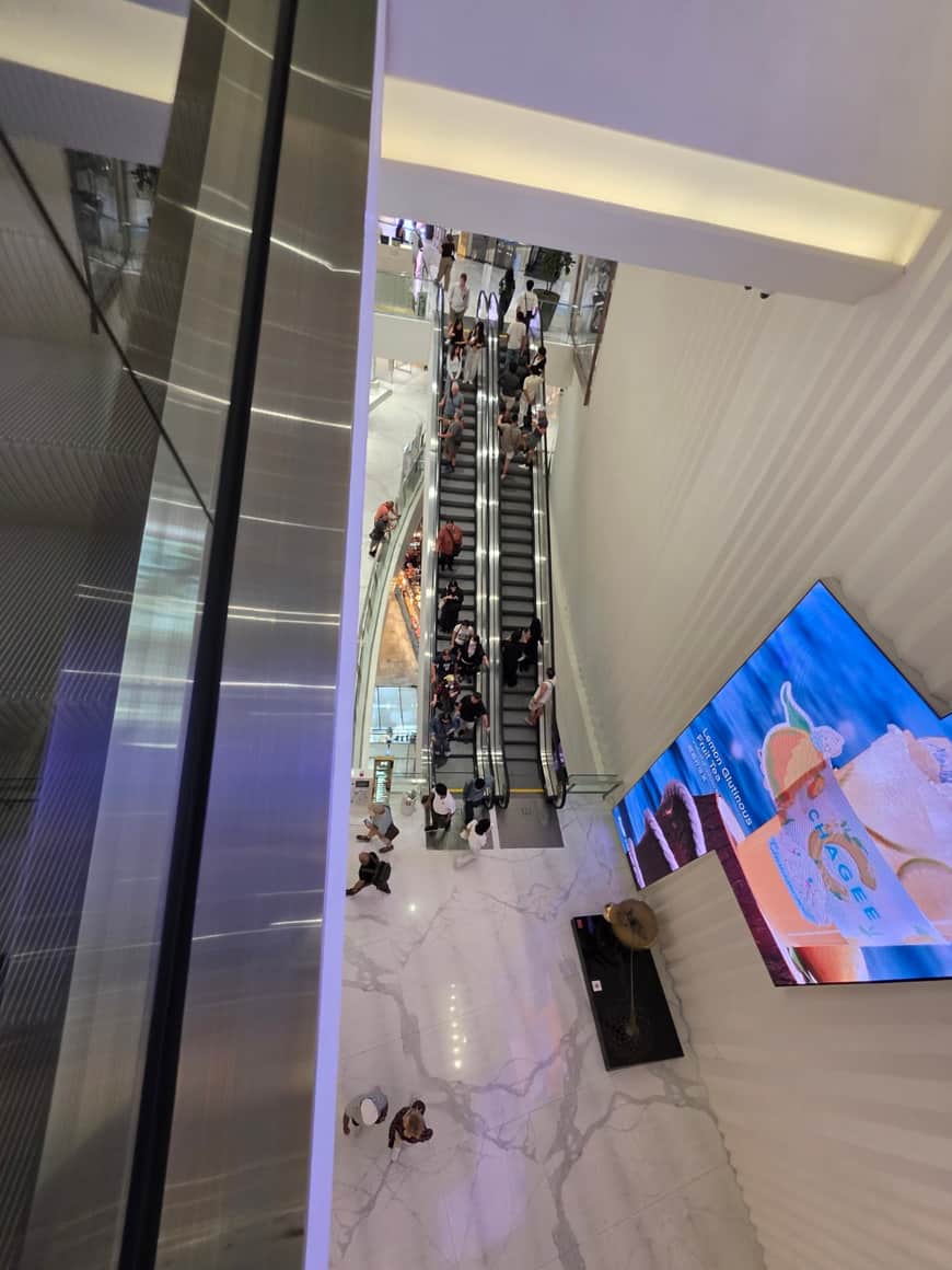 Vue inclinée d’un espace commercial avec panneaux lumineux et parois vitrées.