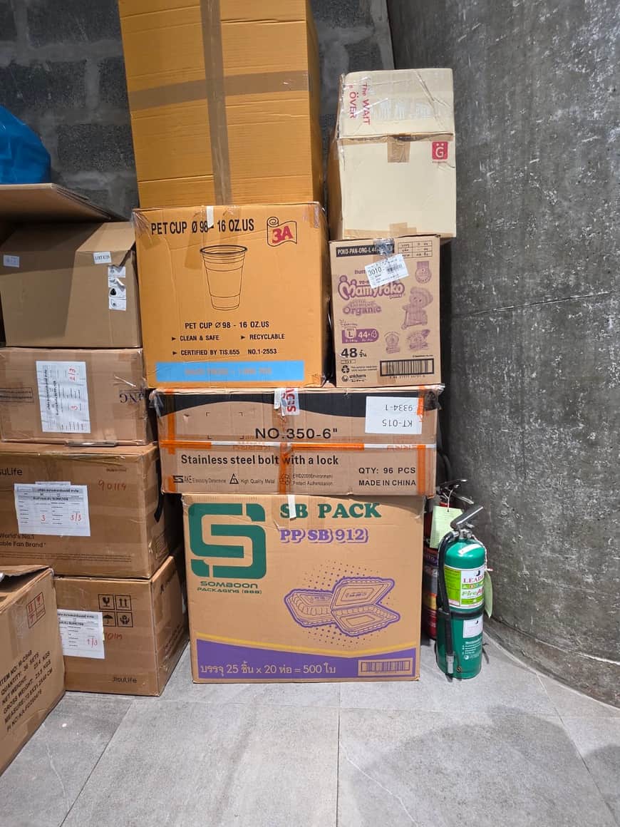 Cartons et bouteille empilés au bord d’un passage intérieur.