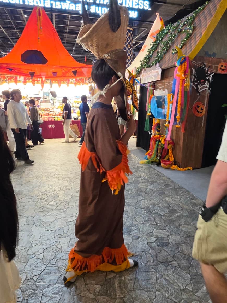 Personne vêtue d’une robe safran parmi des stands et des visiteurs.