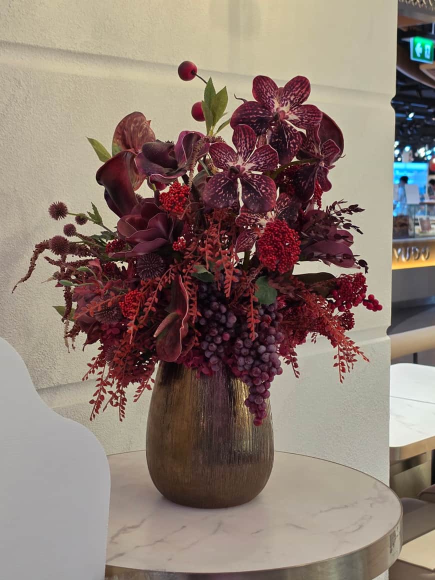 Composition florale sombre dans un vase, en salle d’exposition.