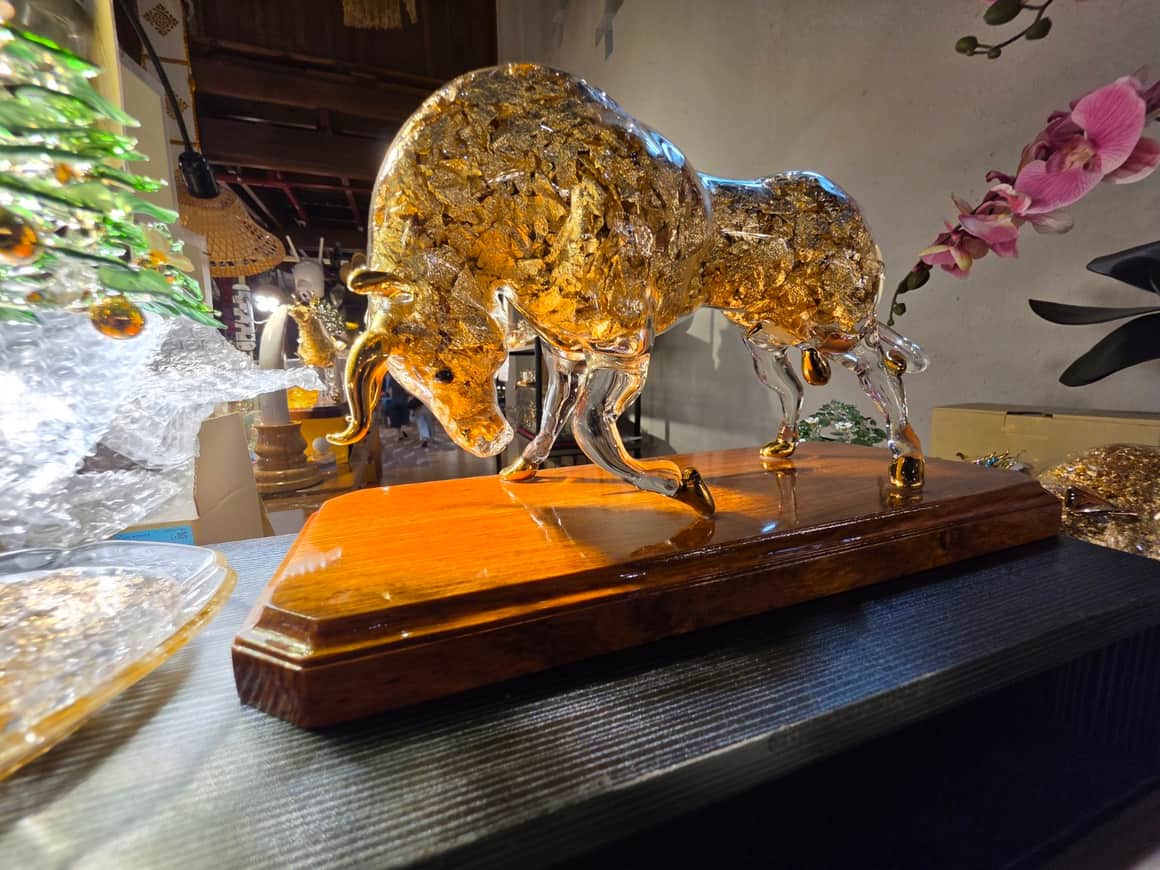 Figure animale dorée exposée sur un socle en bois.