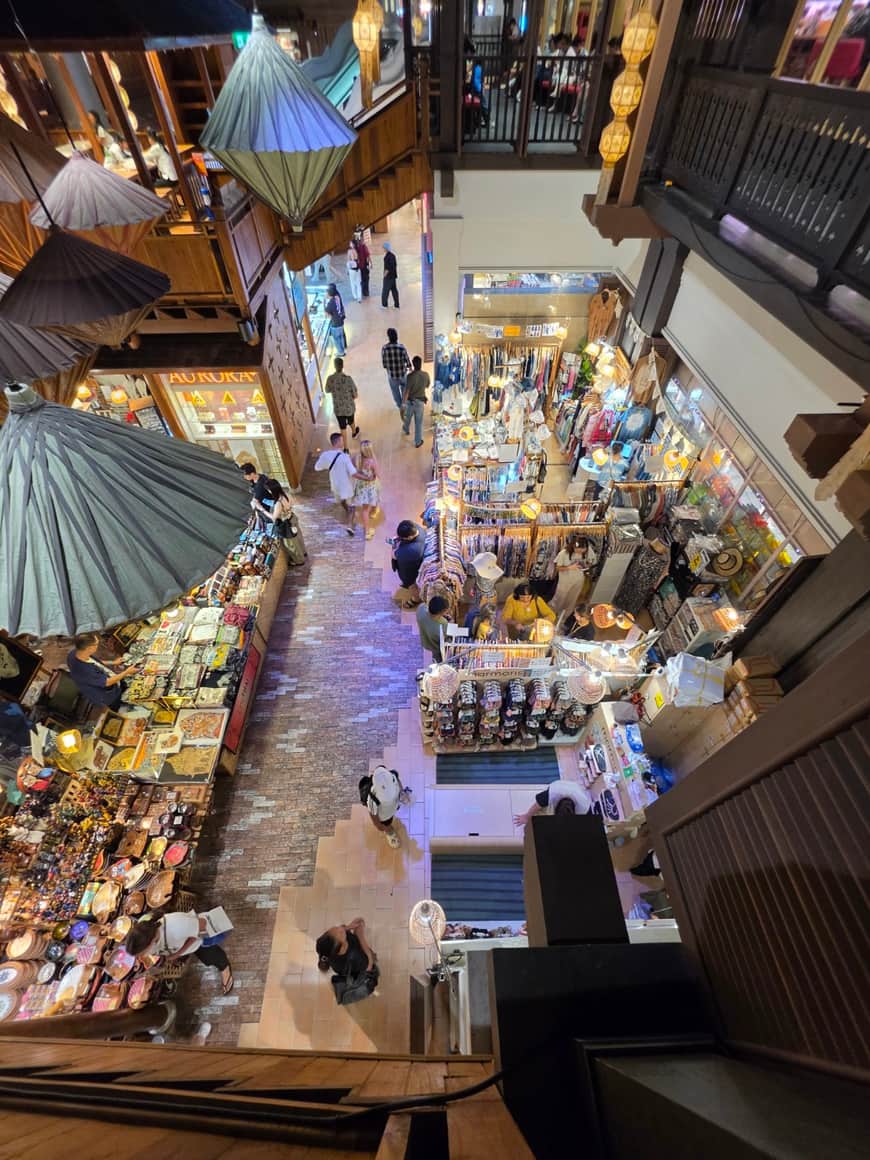 Galerie commerciale vue depuis un étage, boutiques et visiteurs en contrebas.