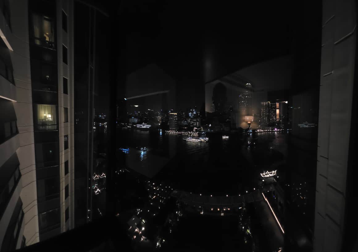 Vue nocturne de la ville à travers une vitre, avec des reflets.