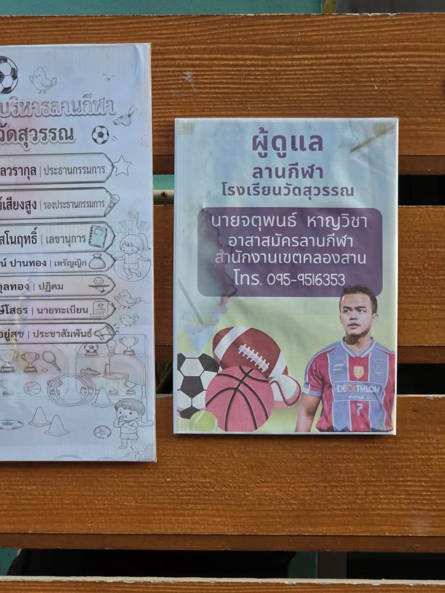 Deux affichettes en langue thaïe sur un panneau de bois.