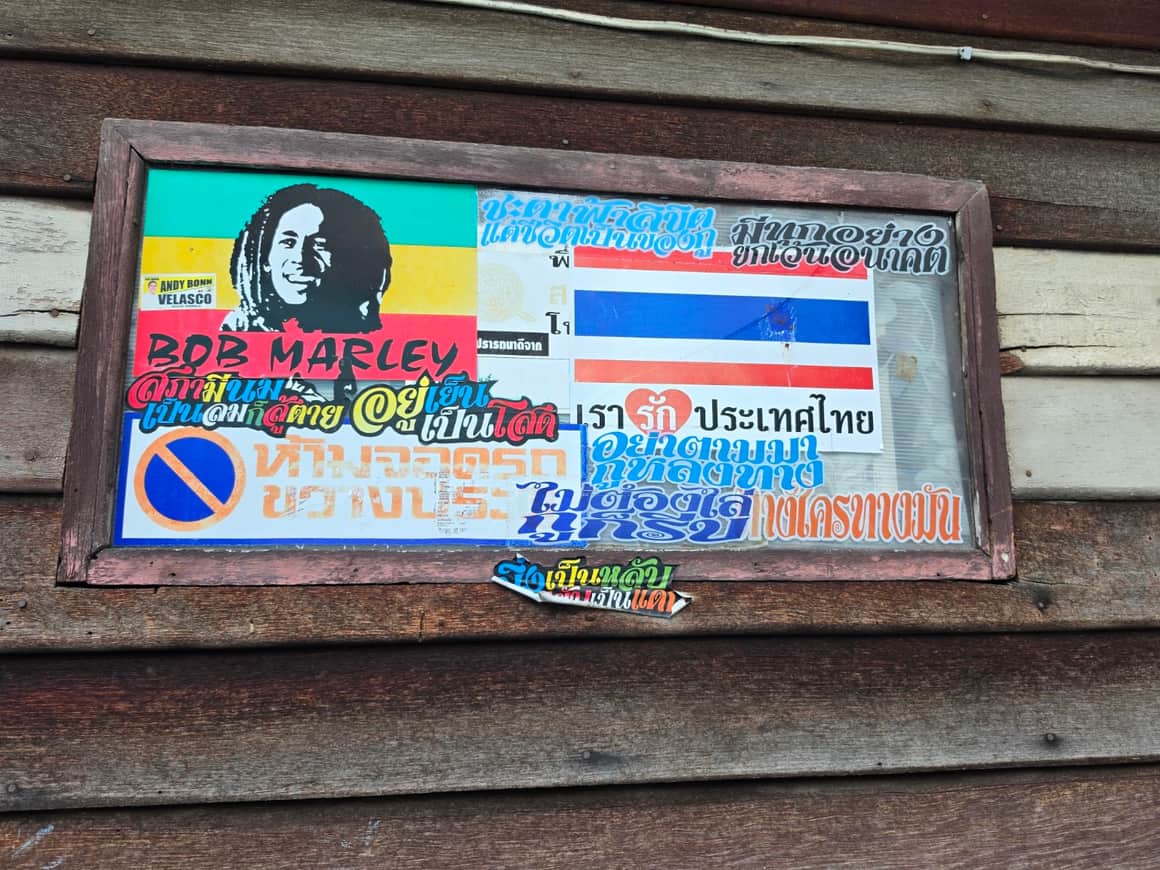Plaque colorée et signes peints sur un volet de bois.